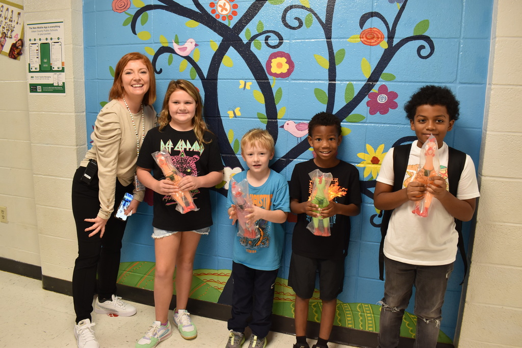 Students holding chicken toys with principal.