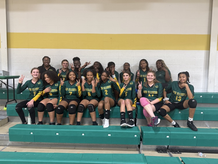 volleyball team smiling and sitting on bleachers 