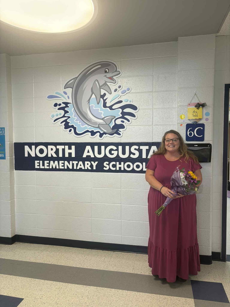 Happy Retirement teacher standing in front of NAUE sign