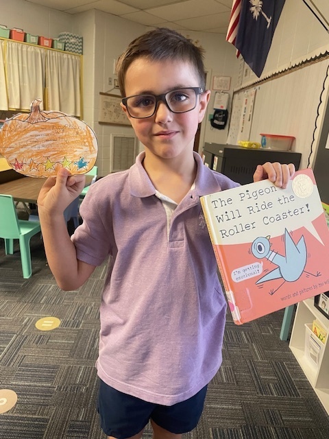 Student holding a book and pumpkin book review