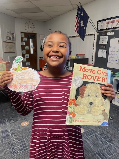 Student holding a book and pumpkin book review