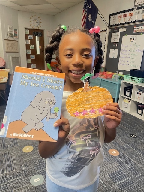 Student holding a book and pumpkin book review