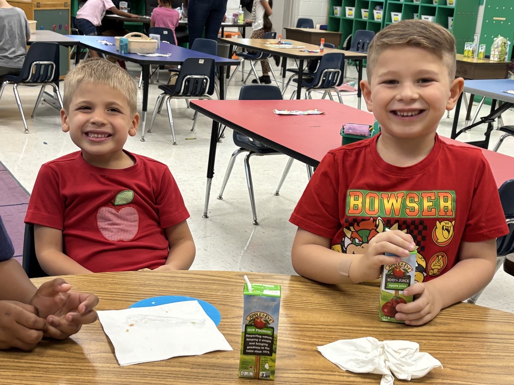 Two students smiling drinking apple juice.
