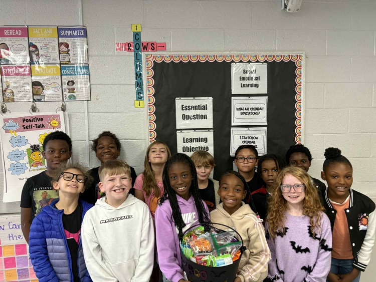 3rd grade students holding a black cauldron full of goodies! 
