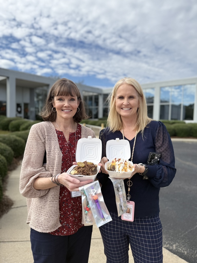 Two staff members standing outside with their potatoes. 