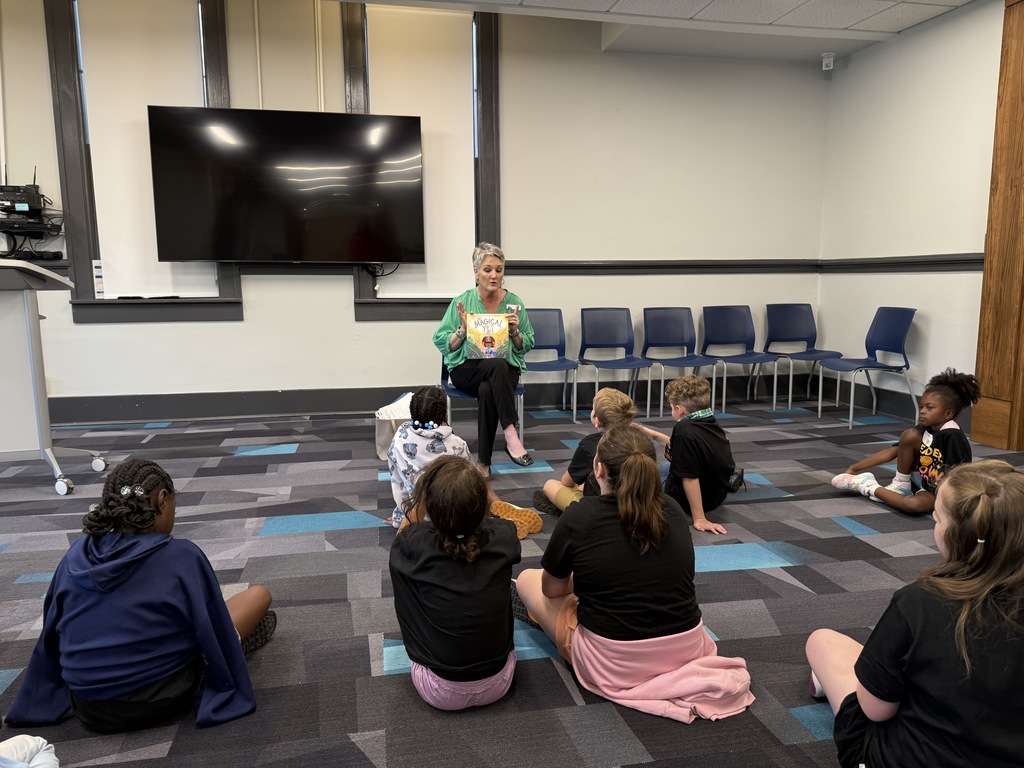 Adult female reads to students at storytime. 