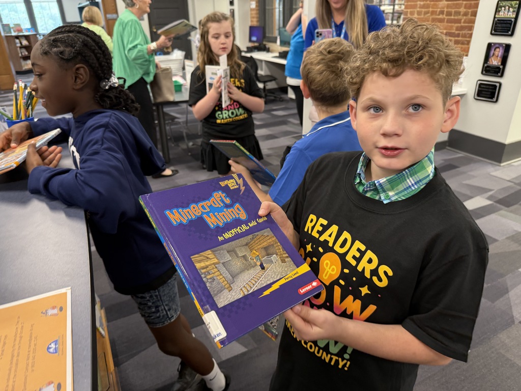 Male student shows library book. 