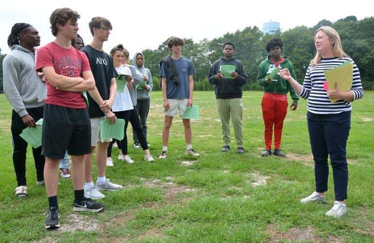 Teacher speaking to a group of students in a field.