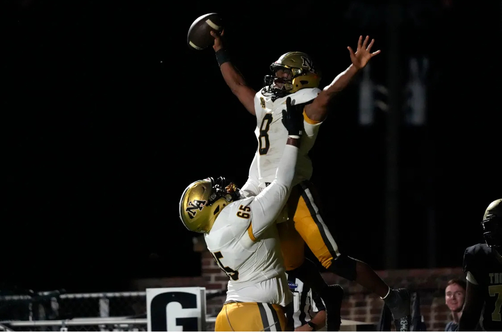 One football player cheering while another holds him up.