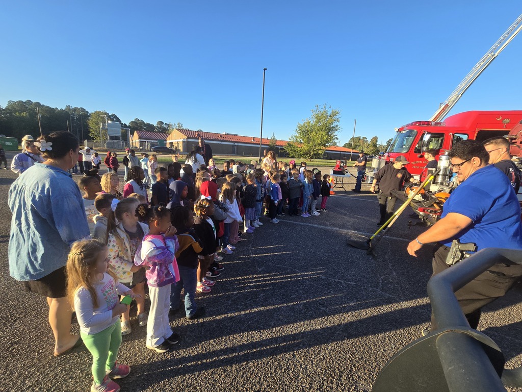 Students and teachers standing in front of fire trucks and firemen.