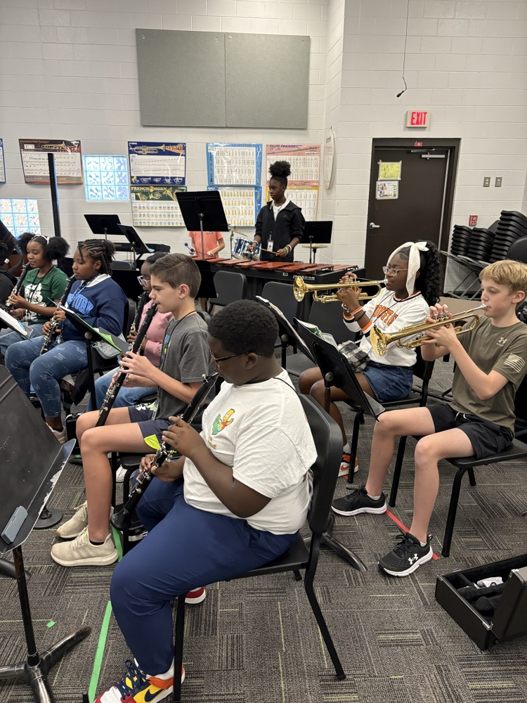 students sitting in a band class playing band instruments 