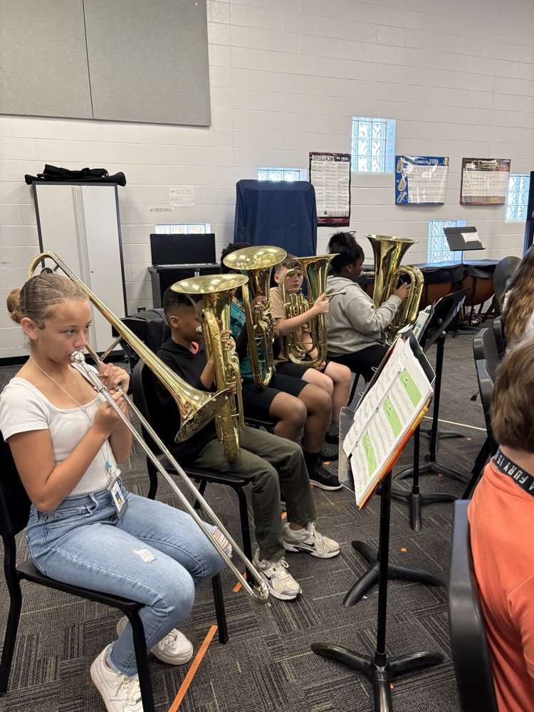 students sitting in a band class playing band instruments 