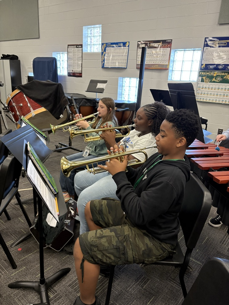 students sitting in a band class playing band instruments 