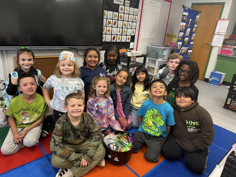 Students sitting on the carpet with a cauldron of goodies. 