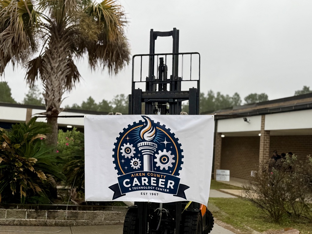 New Logo for the ACCTC is shown on a white backdrop and hanging from a forklift. 