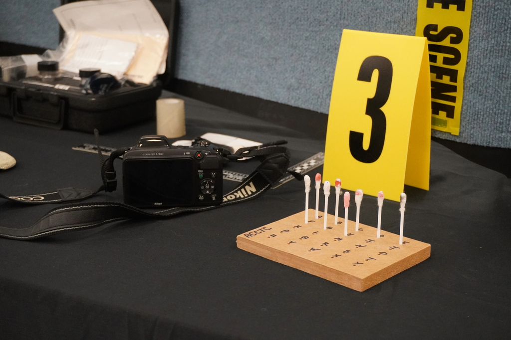 Photo of an exhibit shown in a Forensics class of a camera, a number three and blood samples during Community Night at ACCTC