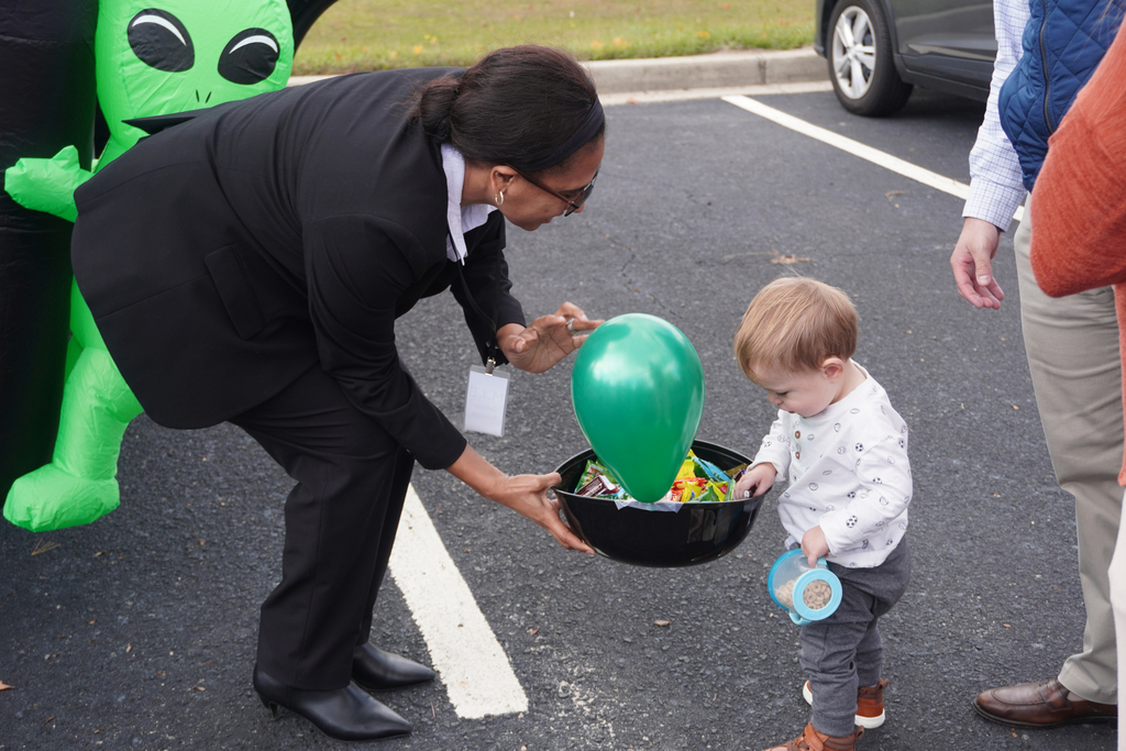 Staff member giving candy to young child.