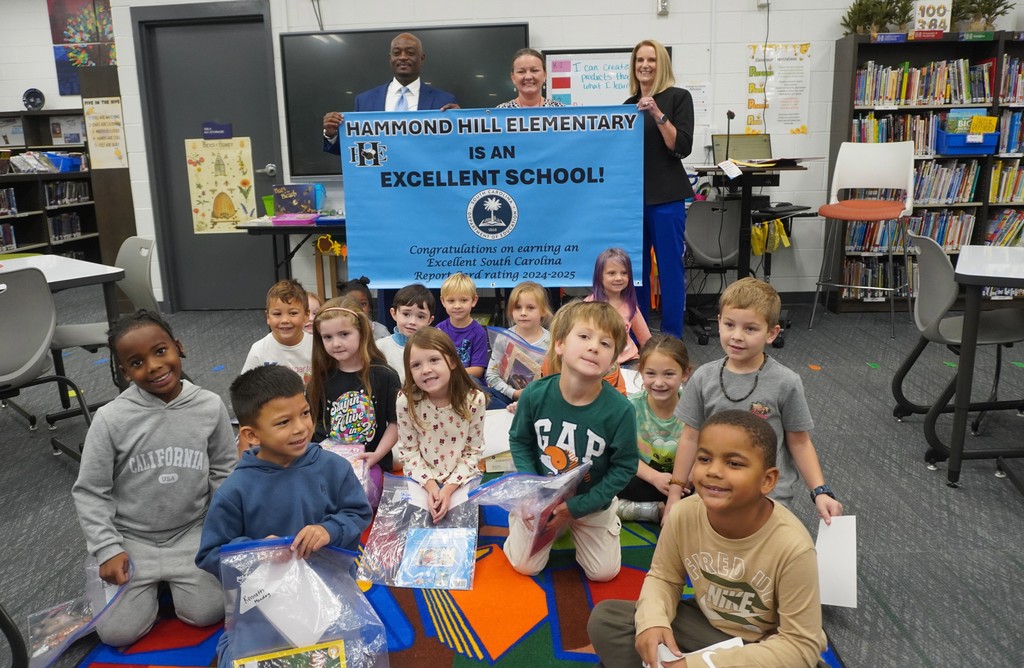 District Leadership and Hammond Hill Elementary principal and students pose with Excellent School Report Card banner.