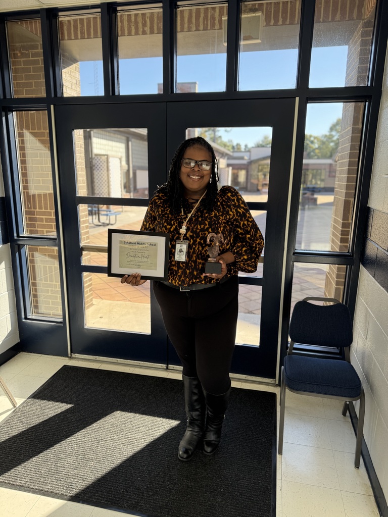 Picture of Ms. Hart holding a trophy and a certificate 