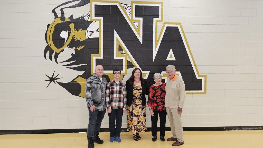 Teacher and family posing in front of NAHS logo.