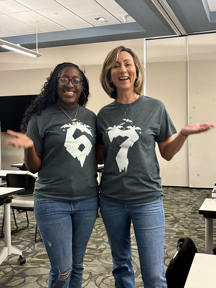 two teachers posing for a picture wearing shirts that say 6-7