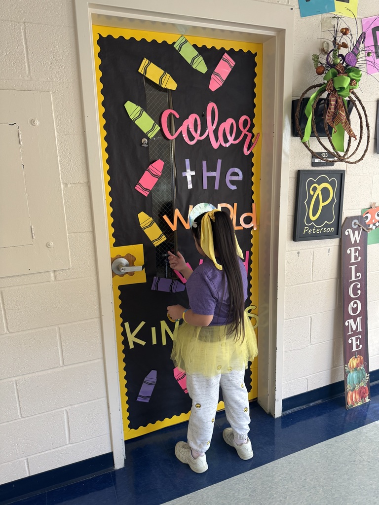 A girl wearing a yellow tutu stands knocking on a classroom door.