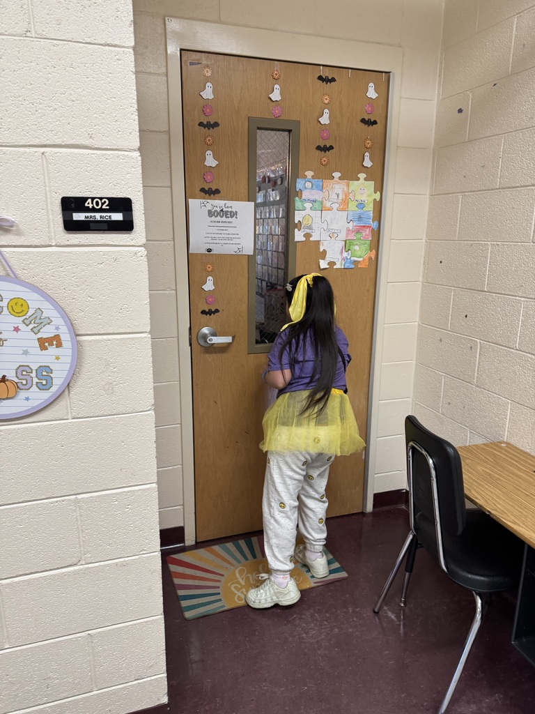 A girl wearing a yellow tutu stands knocking on a classroom door.