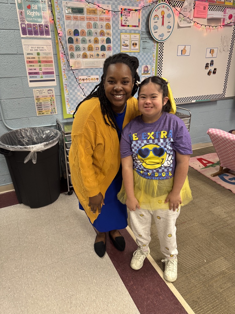 One teacher stands next to a student smiling.