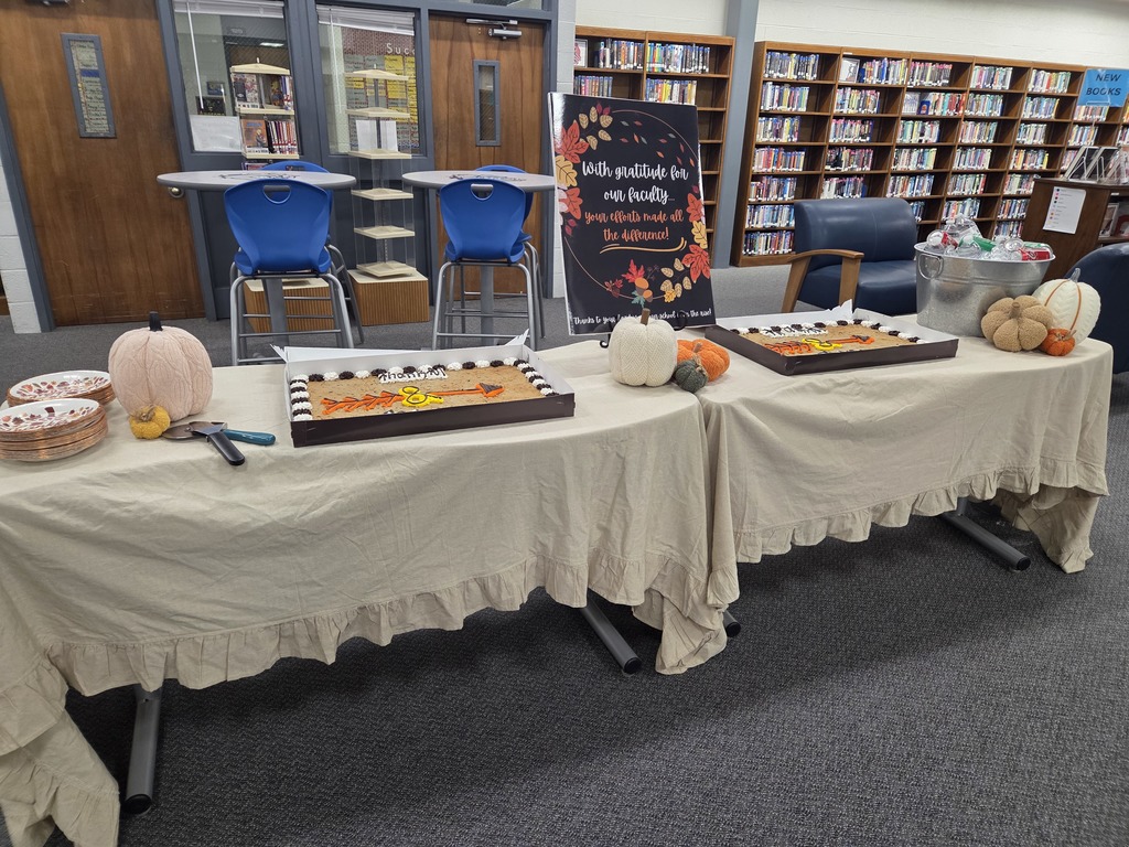 Decorated fall table with pumpkins, cookie cake, and a sign