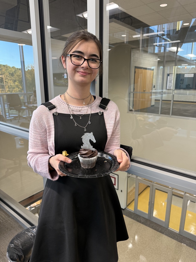 Student smiling holding a cupcake. 