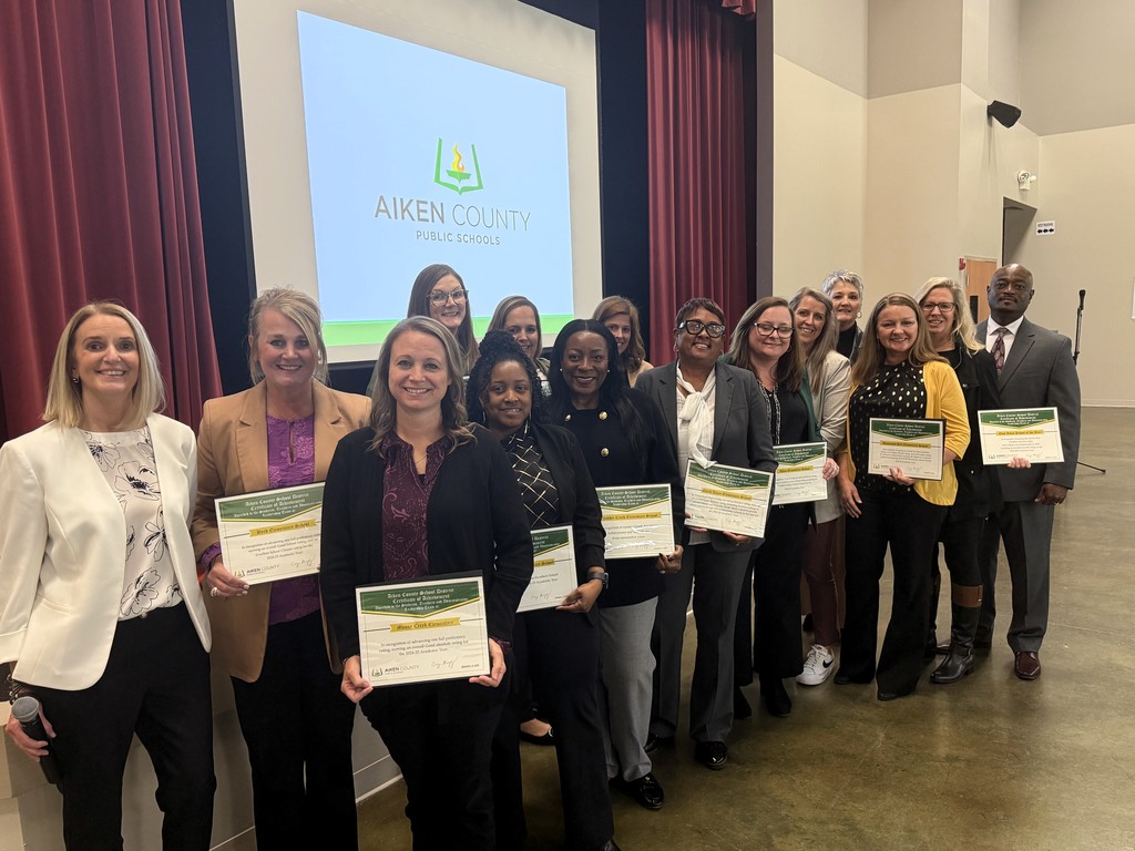 Teachers stand together for a photo with awards. 