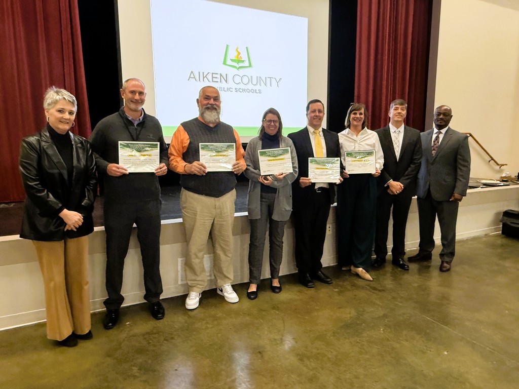 Principals stand together showing their awards.