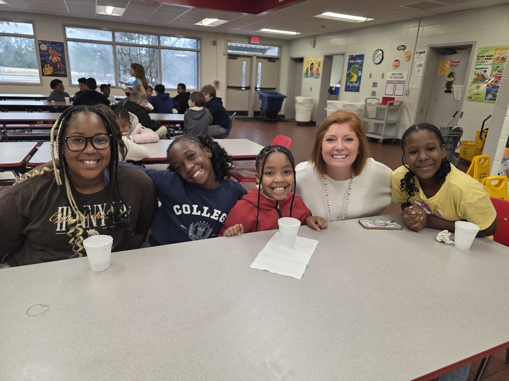 Students drinking hot cocoa at table with principal.