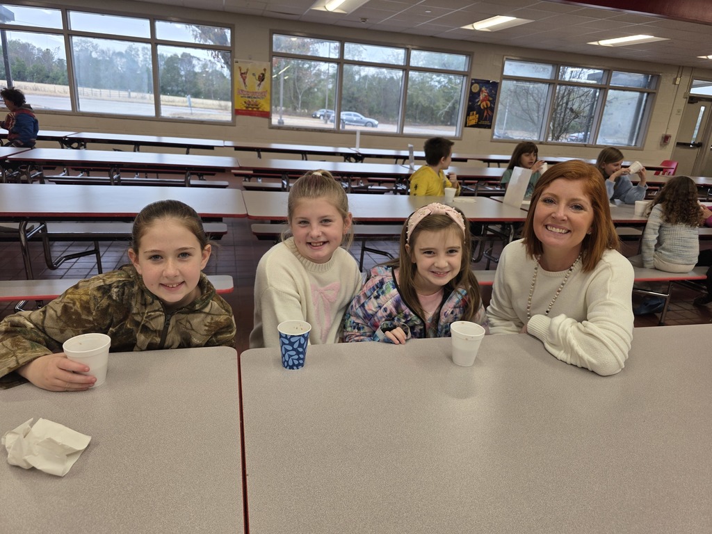 Students drinking hot cocoa at table with principal.