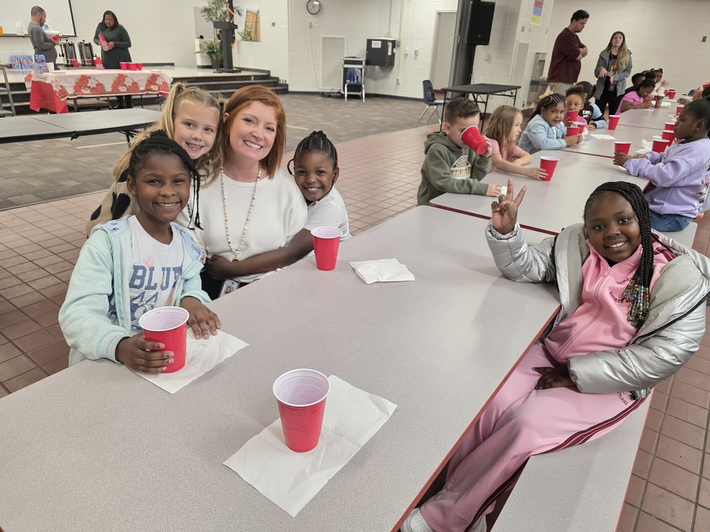 Students drinking hot cocoa at table with principal.