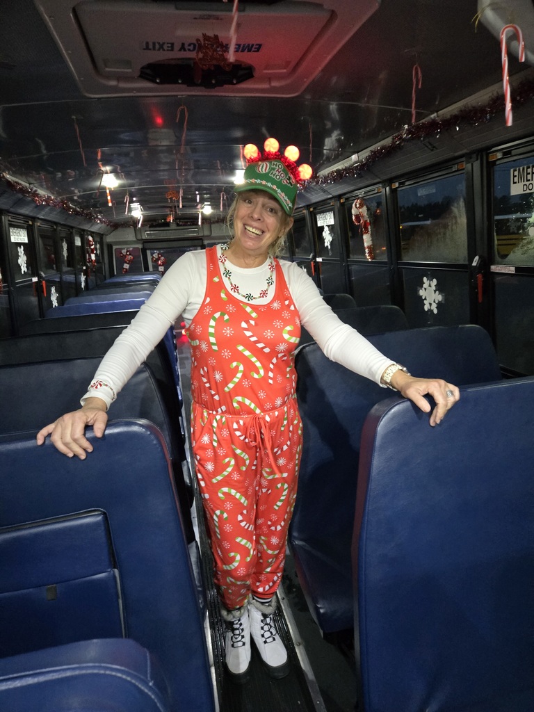 Bus driver in CHrstmas outfit standing on bus.