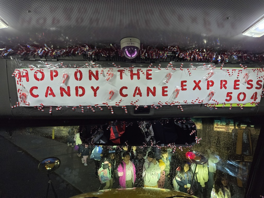 Sign that says "Hop on the candy cane express 504" attached to bus.