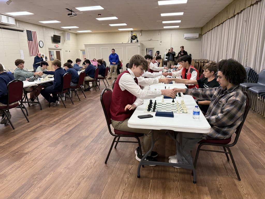 Students playing chess at long tables. 