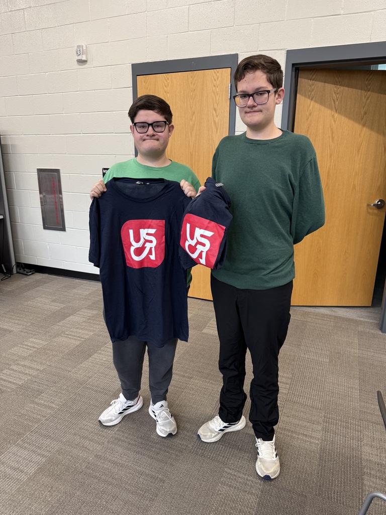 2 Students holding up USCA Shirts.