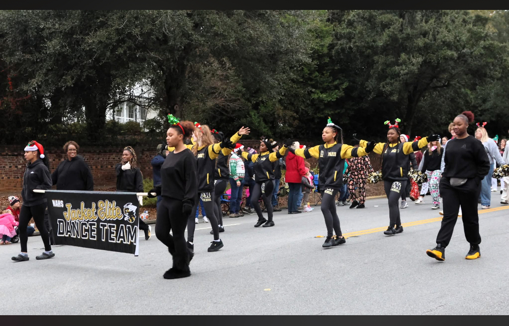 NAHS dance team holding sign wearing black and yellow marching in a parade.