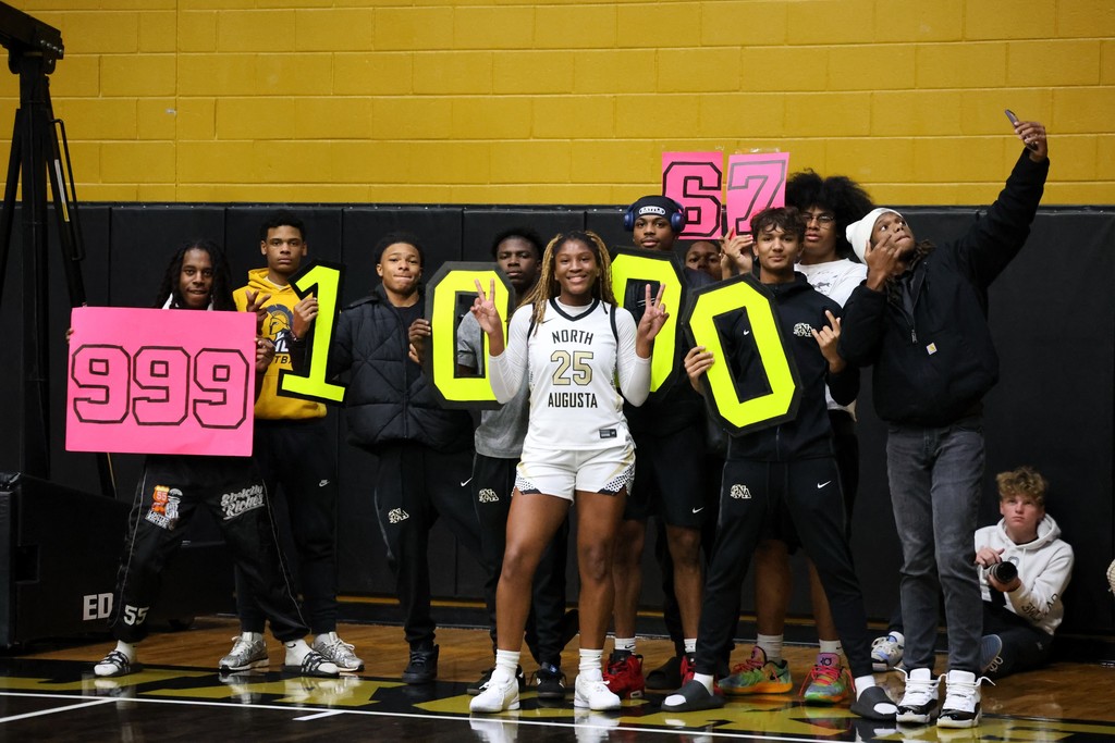 Group of students holding 1000 sign with girl basketball player in front.