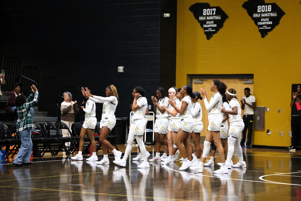 Girl basketball players running up to coach giving high fives. 
