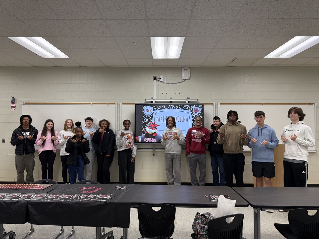 Group of students doing USC hand signal in classroom. 