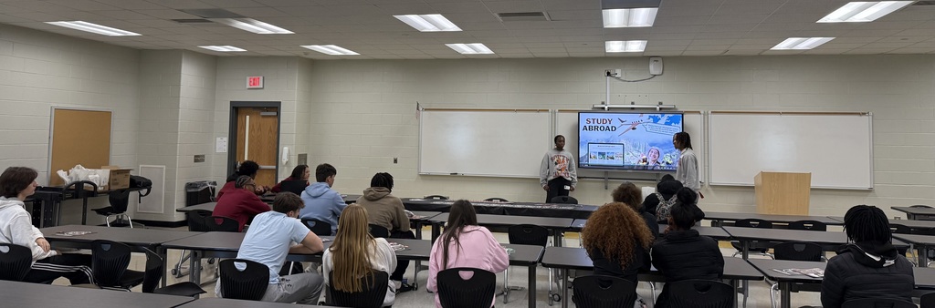 Students teaching other students in classroom with smartboard. 