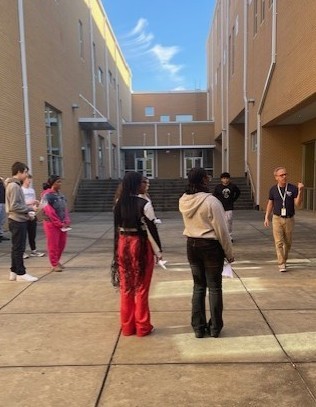 Students flying paper airplanes in courtyard. 