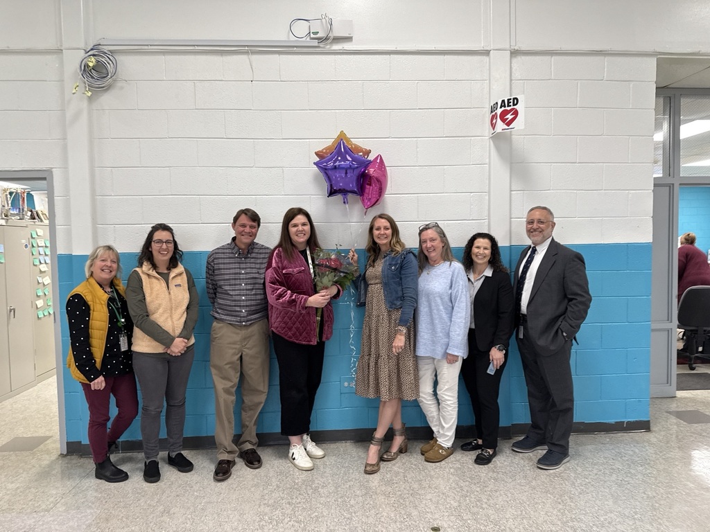 A group of eight educators pose for a picture with balloons. 
