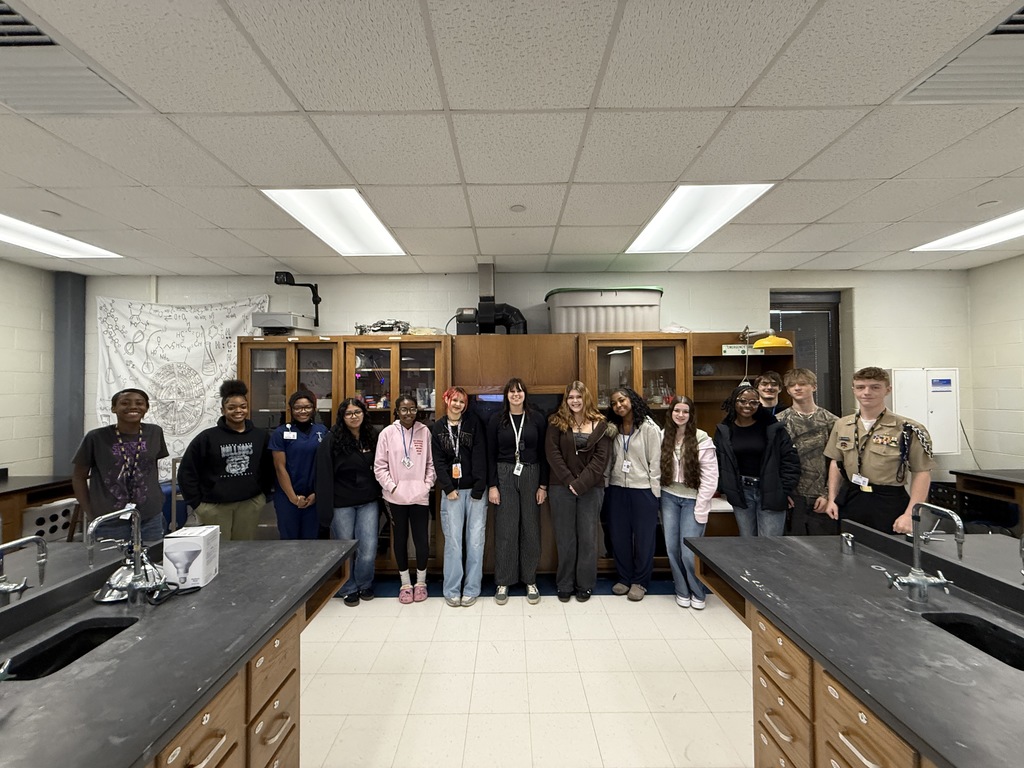 Madison Spires, center, poses a group of 14 high school students  in science class. 