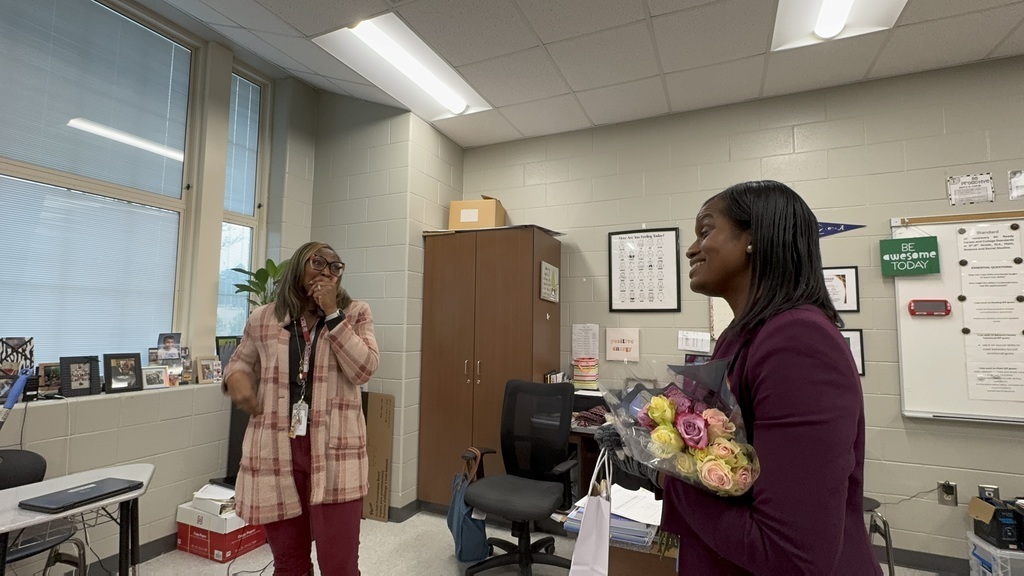 Sonya Lee, left, appears surprised in her classroom when Kayla Jordan, right, surprises her with flowers and the announcement she's on the Teacher of the Year Honor Court.