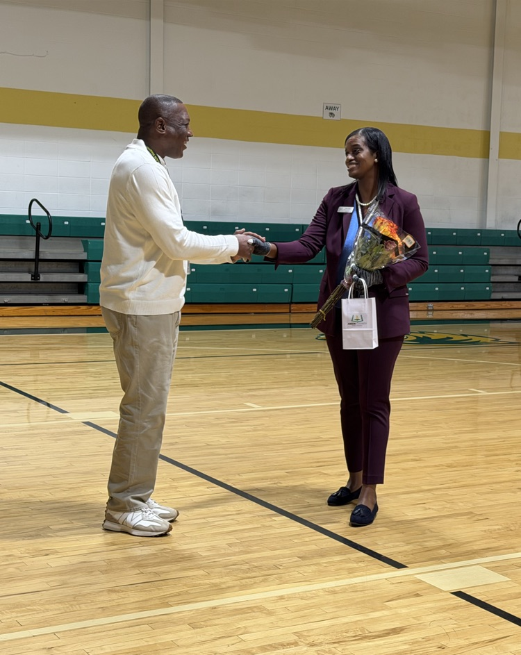 man receiving an award from a woman in a gym 