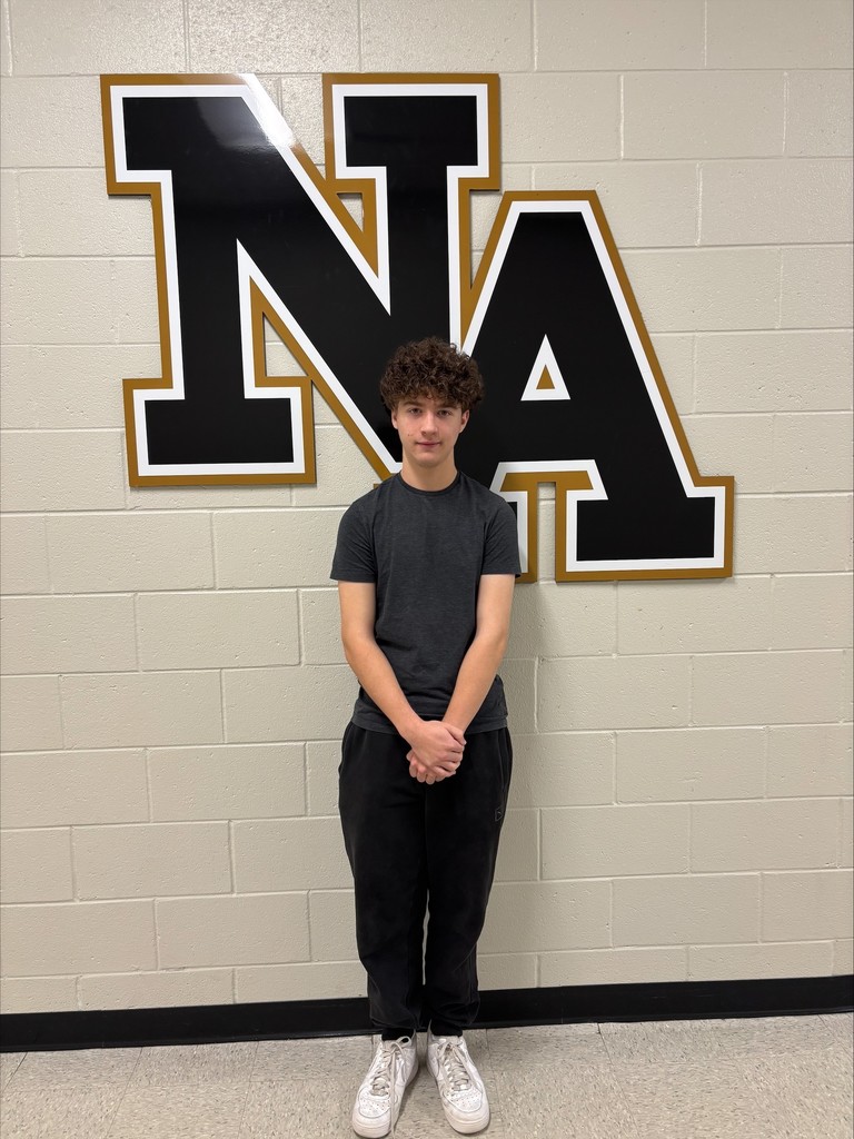 Student posing in front of NA sign.